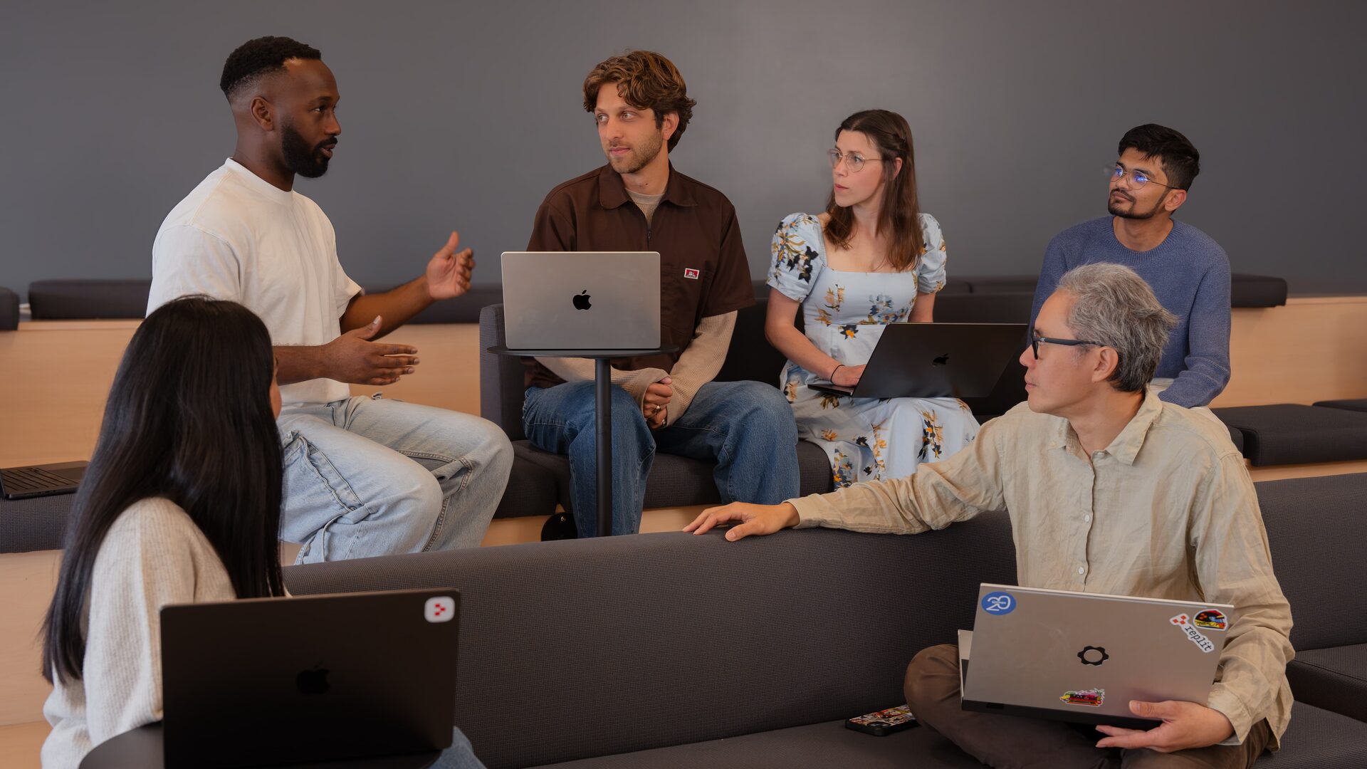 Teammates in a lively discussion around laptops in an office lounge