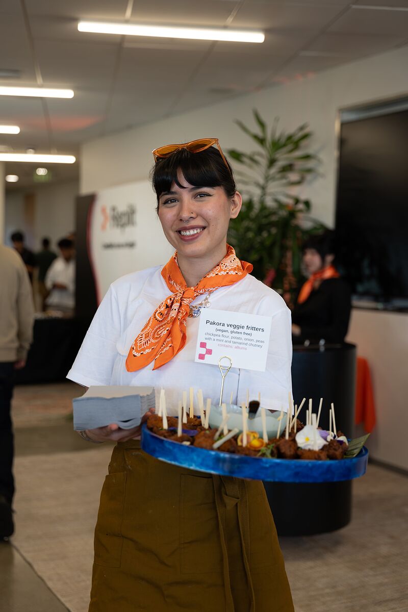 Event staff smiling while offering a tray of appetizers