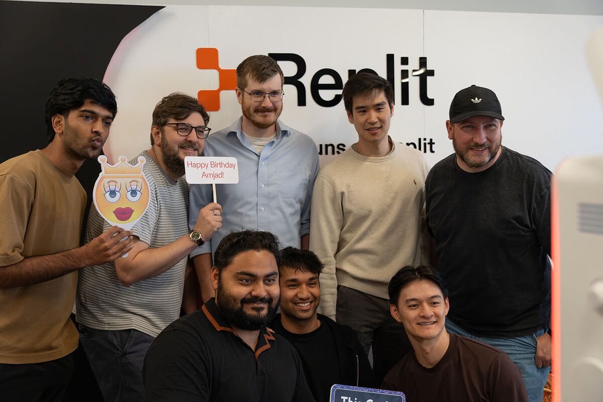 A group of teammates posing at the Replit photo booth with birthday signs