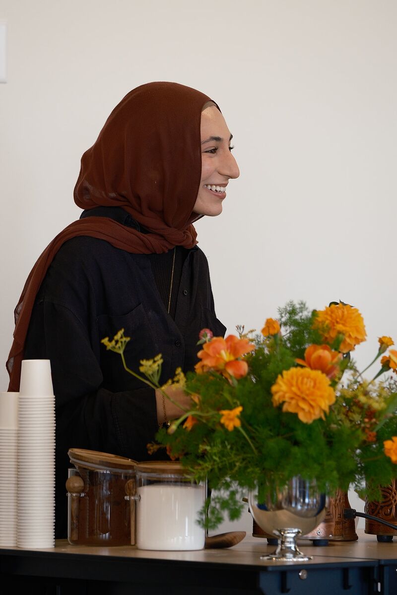 Event staff smiling behind the coffee counter beside bright orange flowers