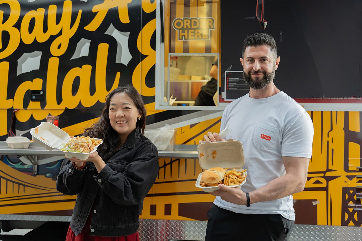 Two teammates smiling and showing off their food truck lunch