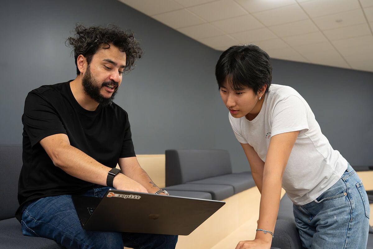 Two teammates leaning in to work through something on a laptop