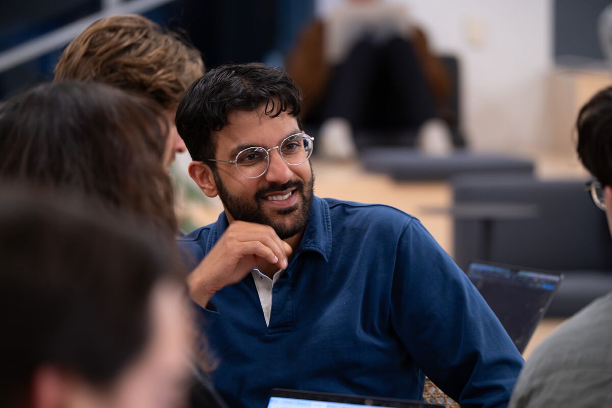 A teammate smiling while listening during a table conversation