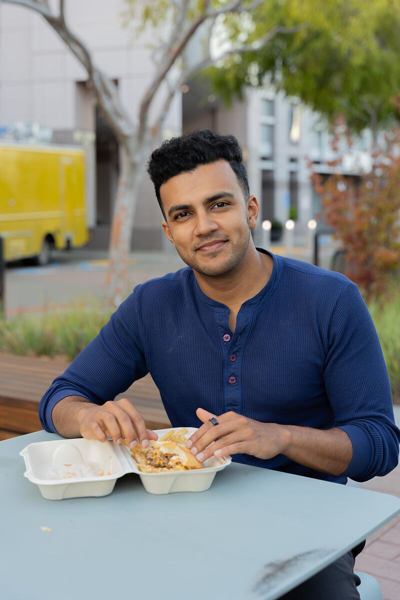 A teammate smiling at an outdoor café table under the trees