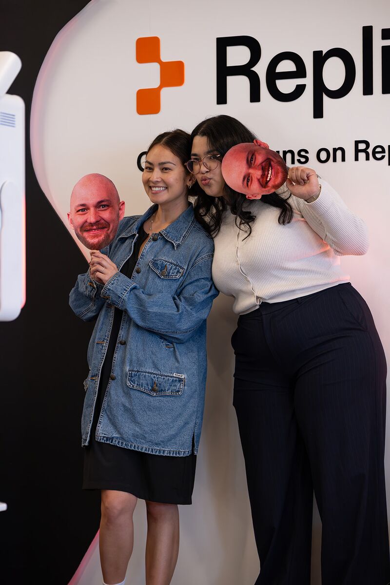Three teammates posing playfully at a Replit photo booth