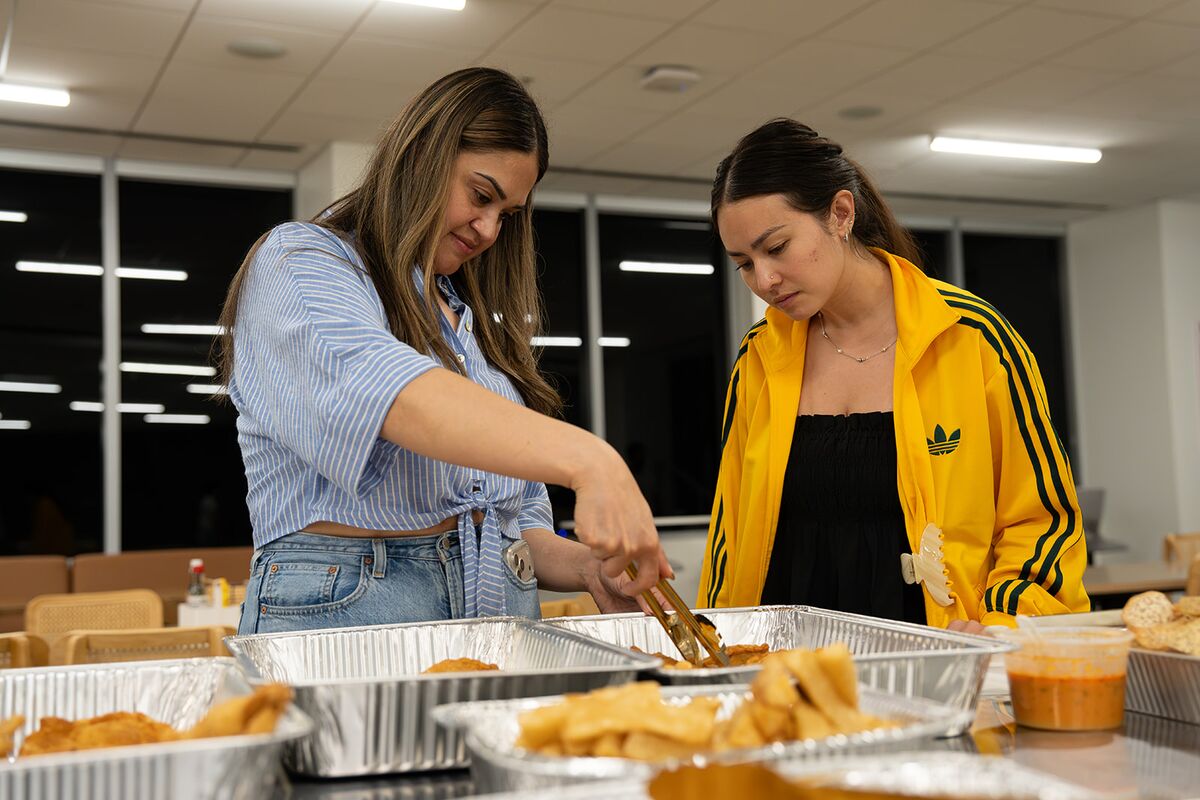 Two teammates serving food from trays at an office lunch