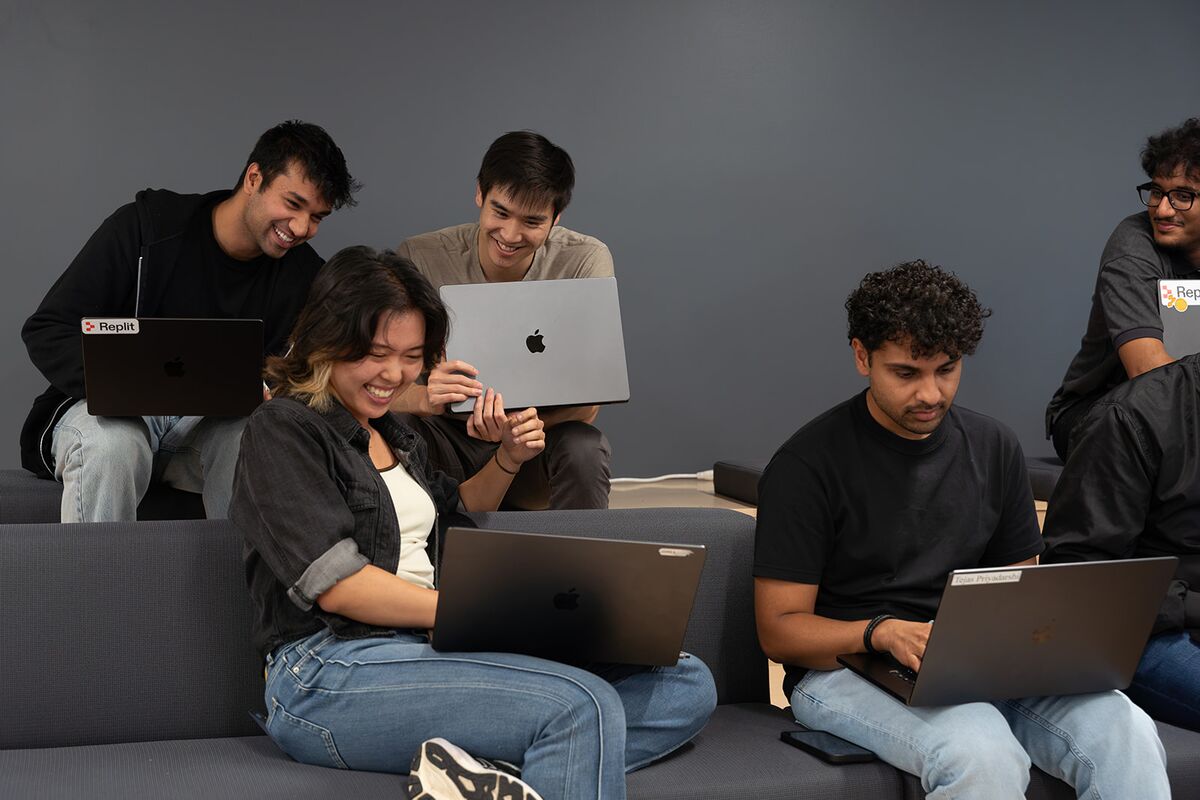 Teammates working side by side on laptops in a lounge