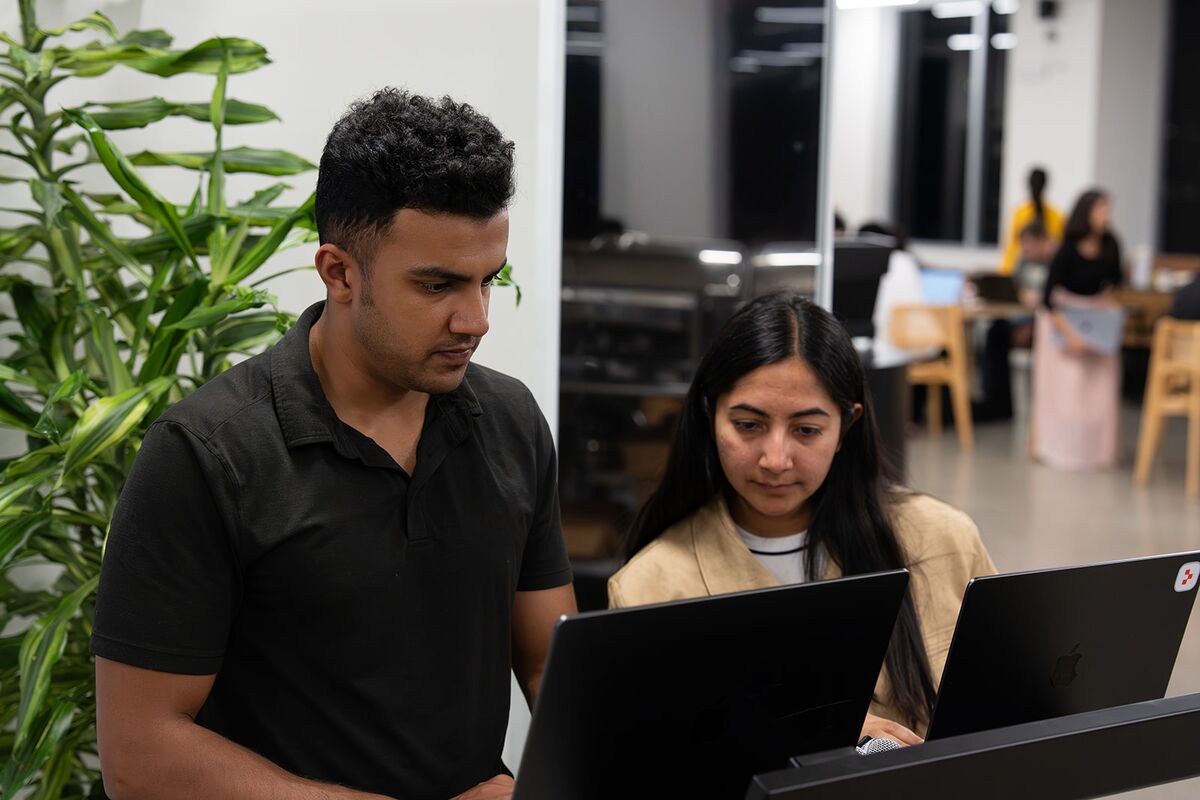 Two teammates collaborating at a plant-lined workstation