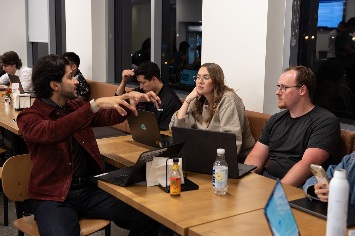 Teammates gathered around a table as one explains an idea with his hands