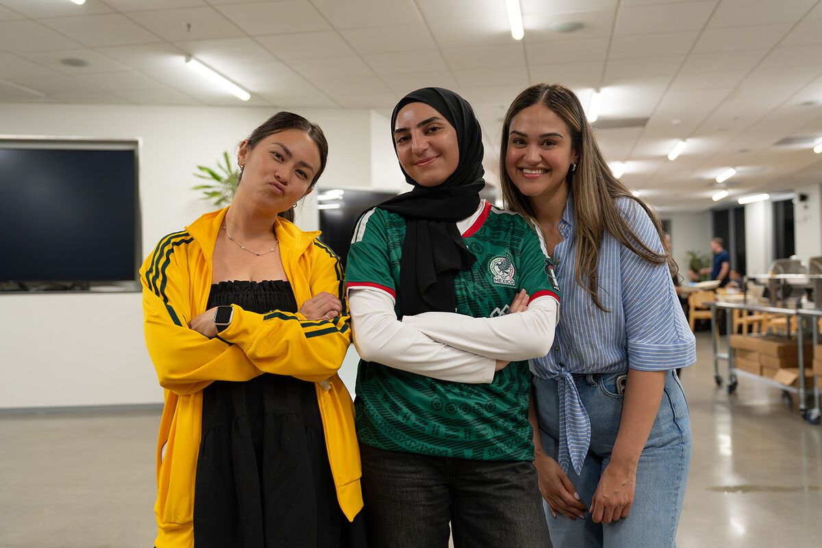 Three teammates posing together and smiling in the office