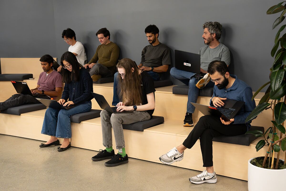 Teammates working on laptops across tiered seating in an open space